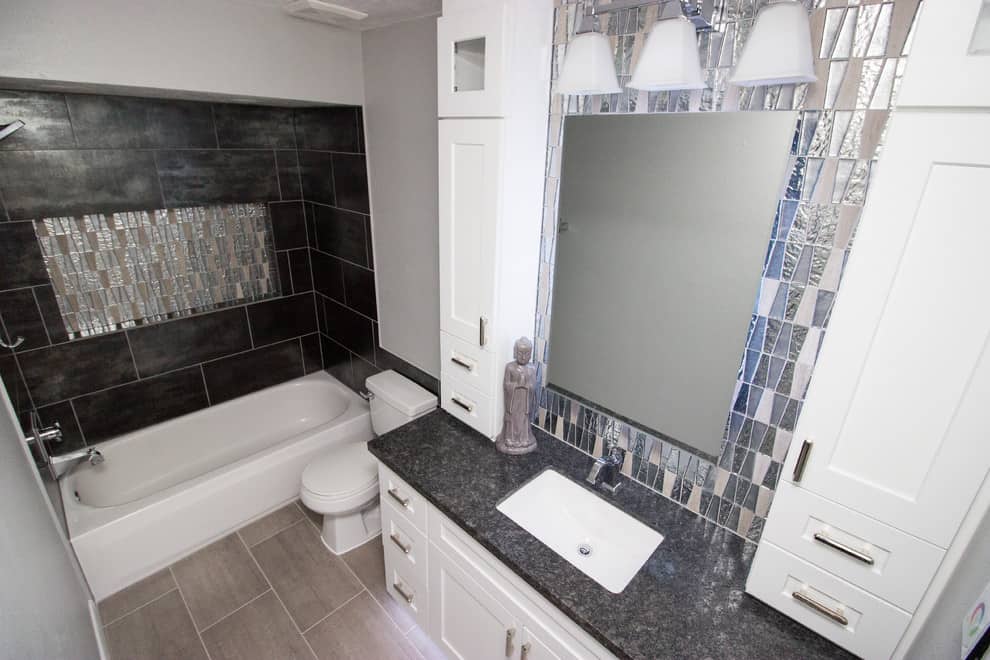 Grey tile floor, black tile walls, white cabinets, granite countertop